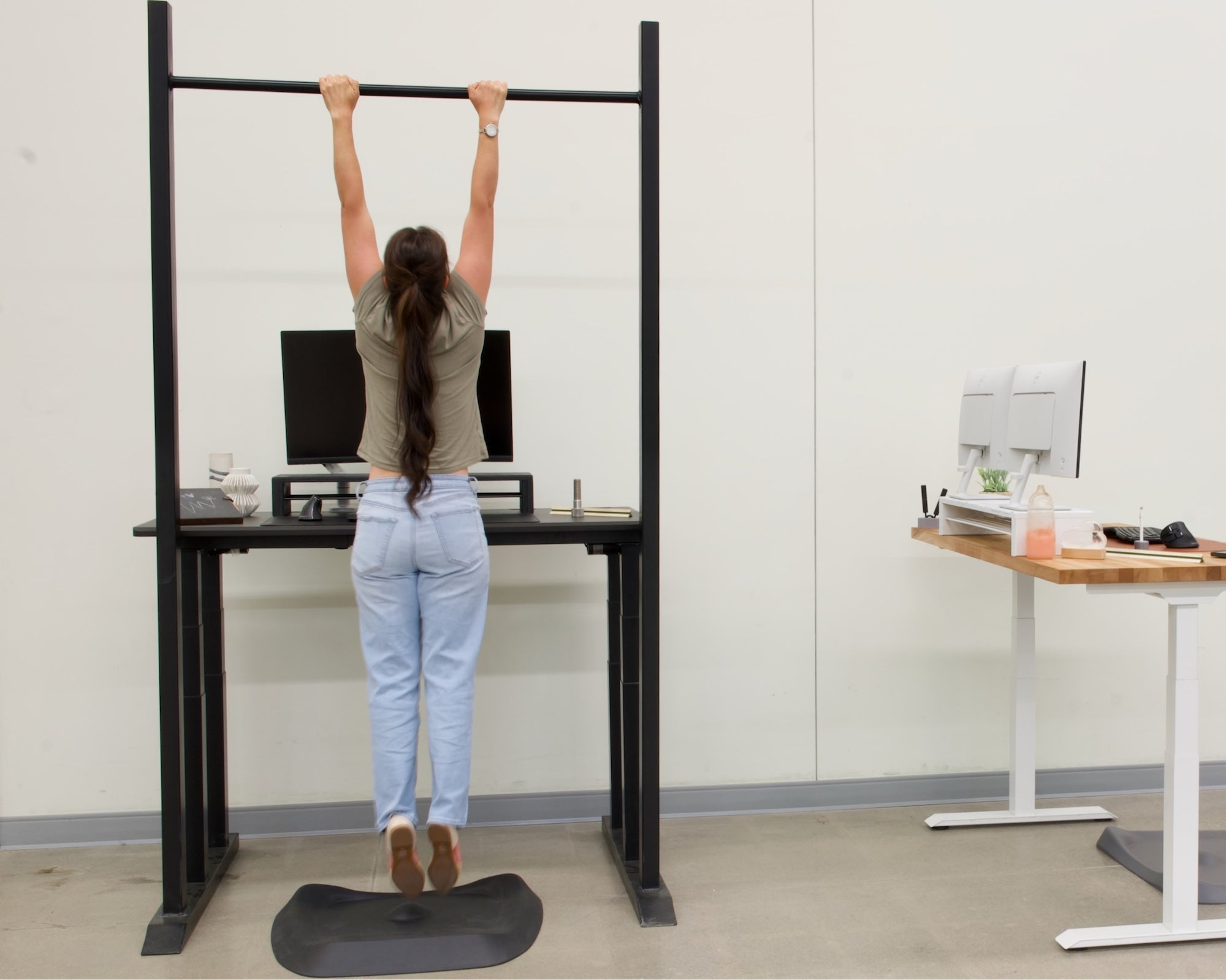 Person using a pull-up bar in an office setting with standing desks.